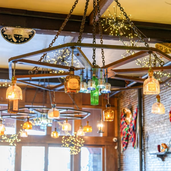 A unique chandelier made from tequila bottles illuminates Gaby's Cafe, with festive lights and decor.