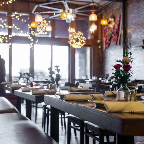 Interior of Gaby's Cafe with set tables, a floral centerpiece, and string lights.
