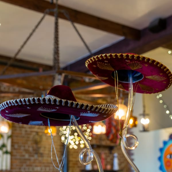 Two ornate, dark red sombreros with gold and silver embroidery hanging as decor in Gaby's Cafe.