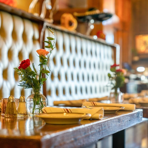 Table set with plates, napkins, salt and pepper shakers, and a vase of flowers at Gaby's Cafe.